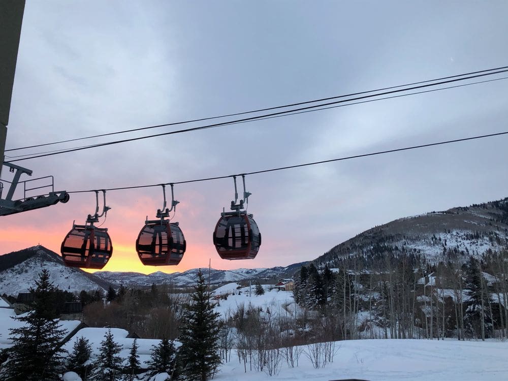 Three gondola cars pass in the distance at sunset in snow-covered Wyndham Park City View.