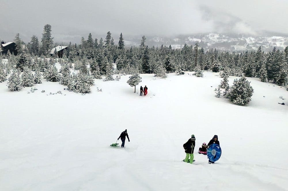 Several kids sled on a snowy hill near Breckenridge.