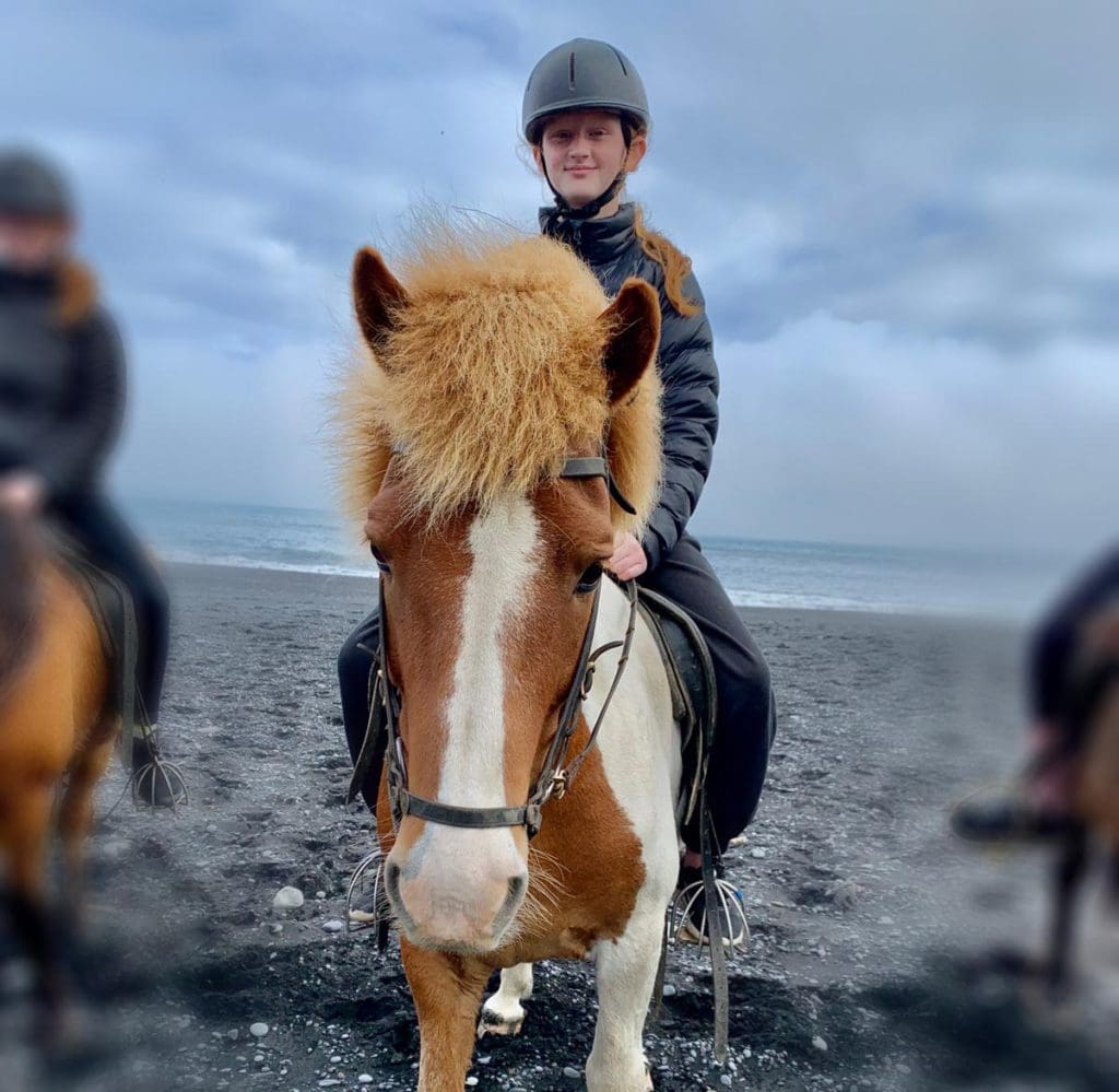 A pre-teen girl rides an Icelandic pony on a tour in Iceland, one of the Best Things To Do in Iceland with Kids.