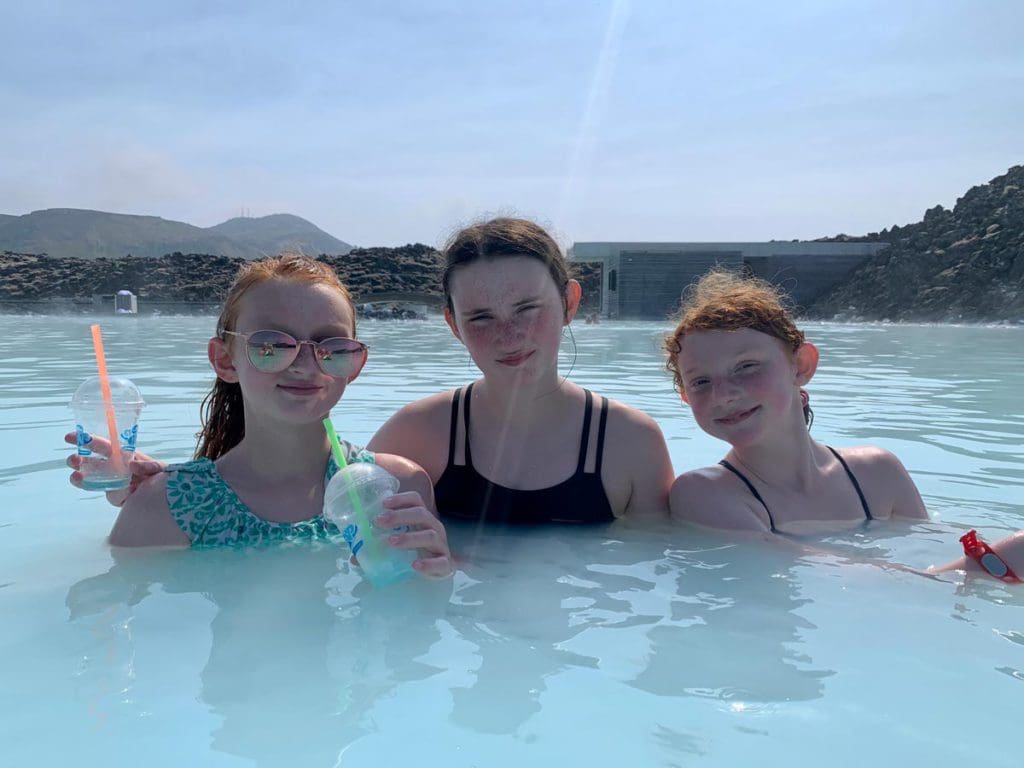 Three pre-teen girls enjoy a hot spring in Iceland.