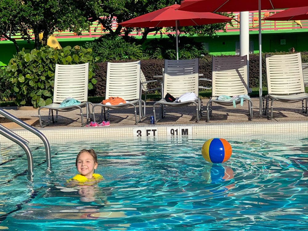 A young girl plays with a beach ball, while swimming in a pool at Disney's All-Start Music Resort.