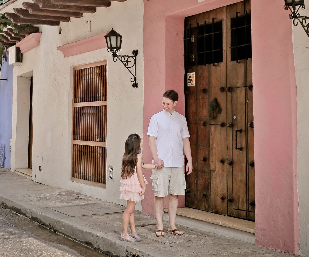 A dad and his young daughter walk down a street in Cartagena.