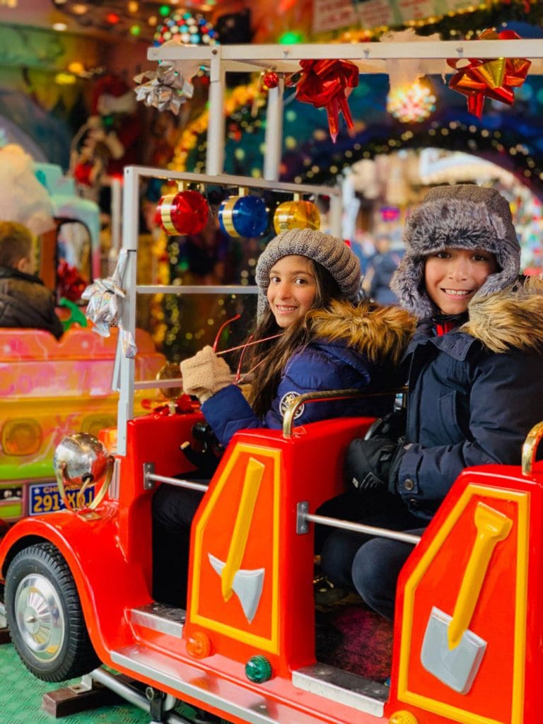 Two kids ride an amusement car at a Christmas market in France.