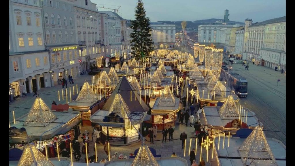 An aerial view of the Linz Christmas Market, featuring lit stalls and a huge Christmas tree.