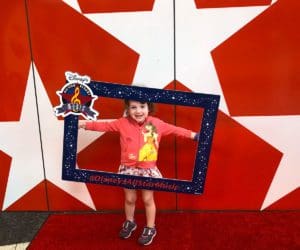 A young girl holds a sign up in front of a star display at Disney's All-Star Music Resort.