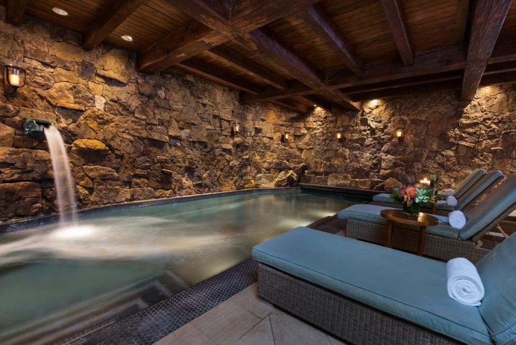 The cozy indoor pool at the Spa Grotto, featuring a water fall and plush pool-side loungers.
