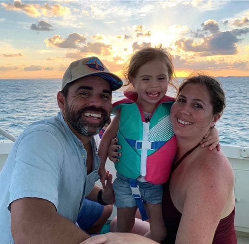 A family of three poses together while taking a sunset boat ride in the Cayman Islands.