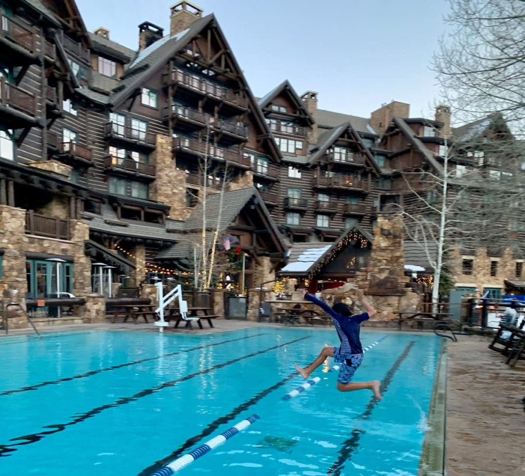 A young boy jumps into a heated outdoor pool at The Ritz-Carlton, Bachelor Gulch.