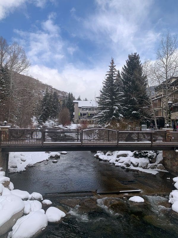A bridge goes over a river in Vail on a snowy day.