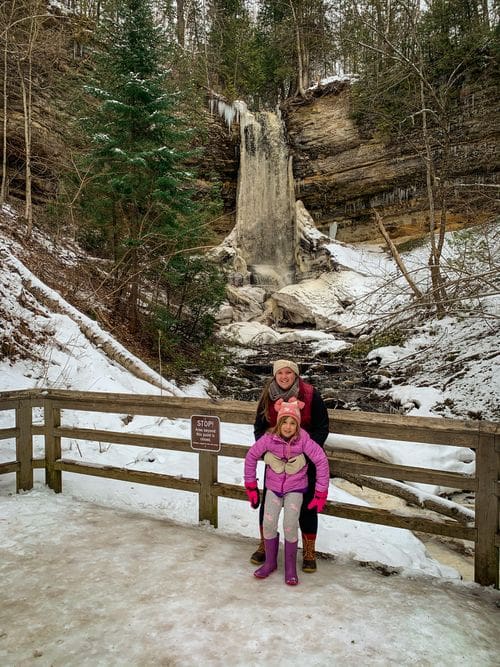 A mom and her daughter stand in front of Munising Falls, one of the best places to visit in Michigan’s Upper Peninsula with kids.