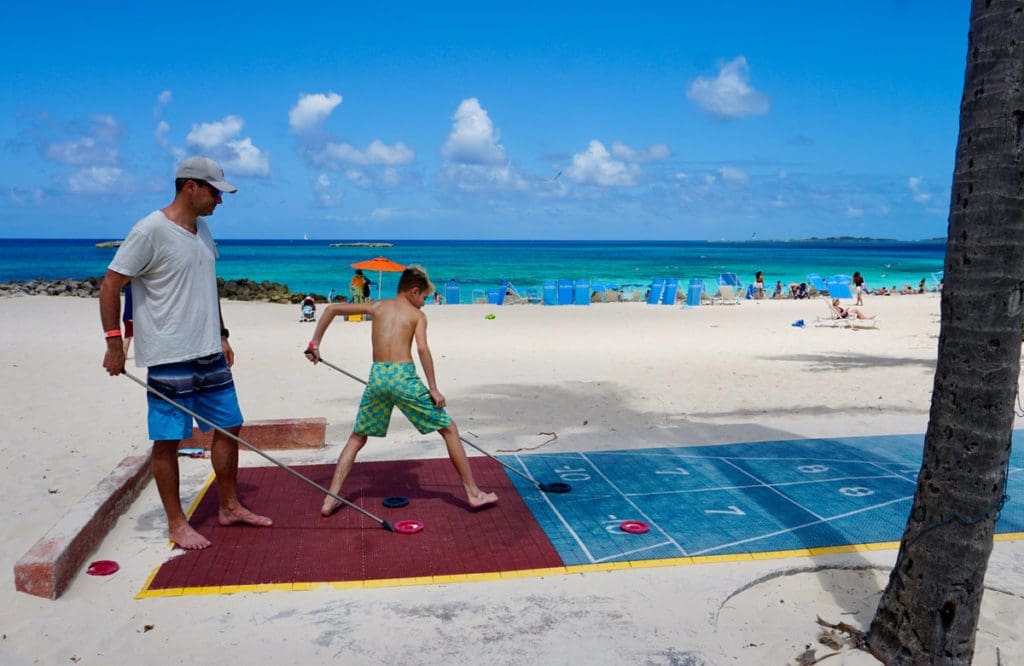 A dad and his young son play shuttleboard at The Coral, one of the best hotels in the Bahamas for families.