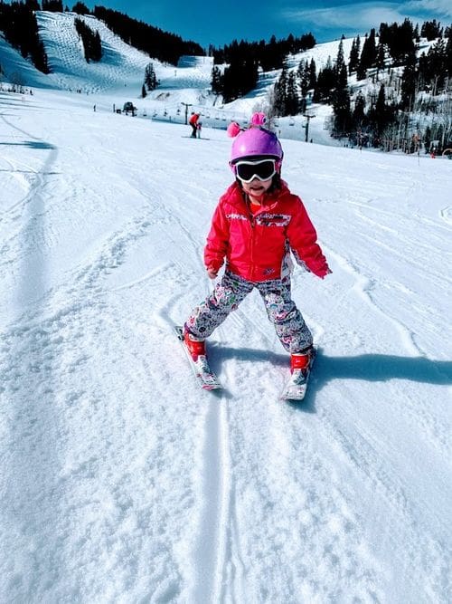 A young skier in full snow gear enjoys a sunny day on the slopes.