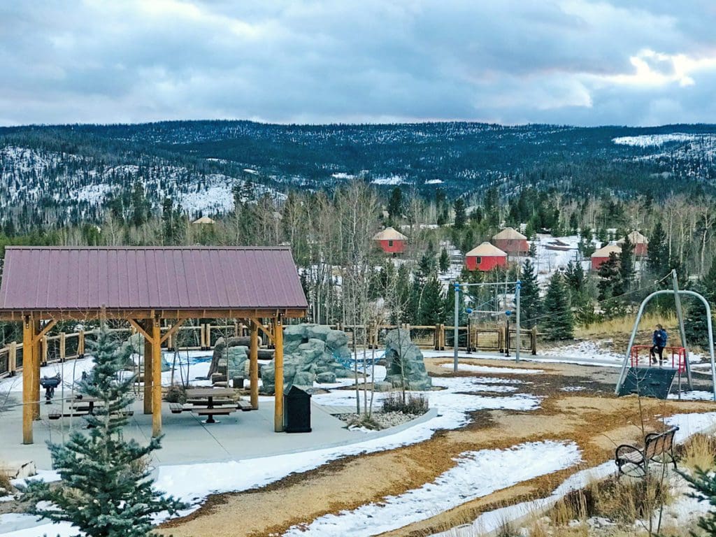 An aerial view of the grounds at YMCA of the Rockies, featuring the yurts, a playground, and a wooded area.