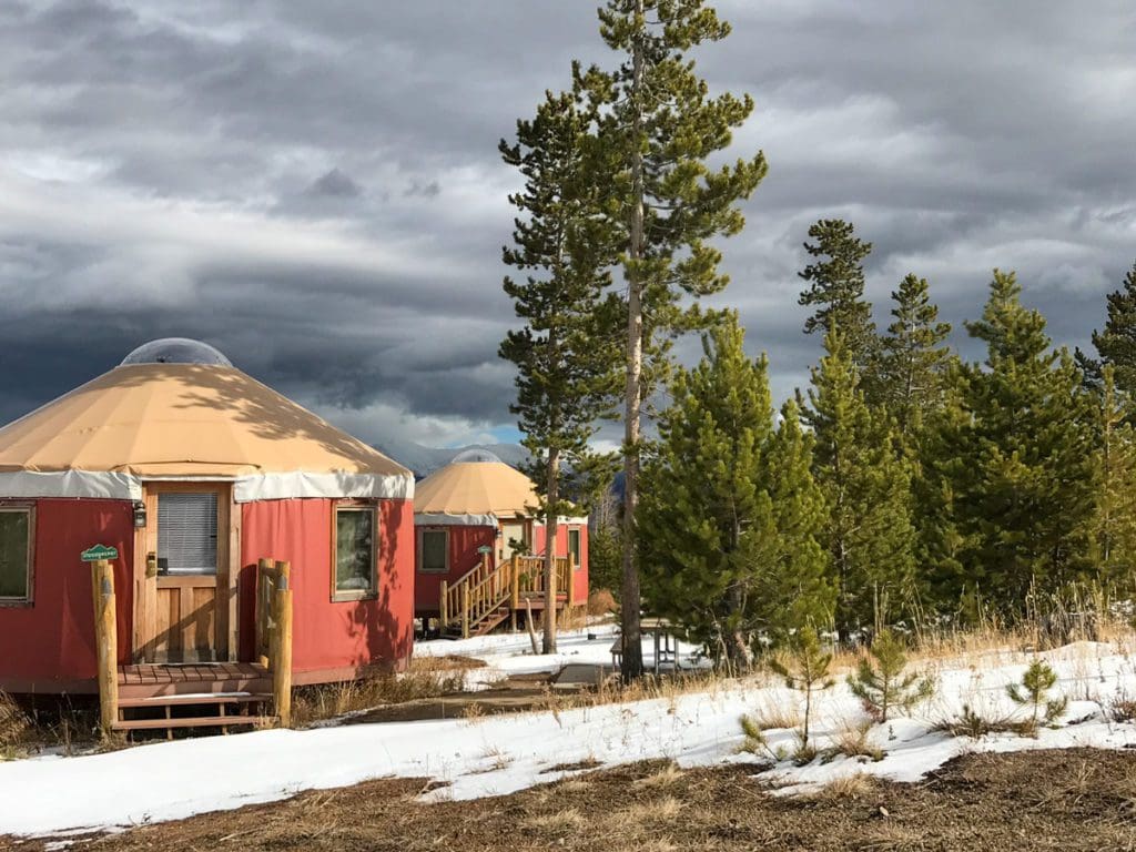 Two red yurts on the grounds of YMCA at the Rockies, one of the best accommodation options at YMCA Snow Mountain Ranch for Families.