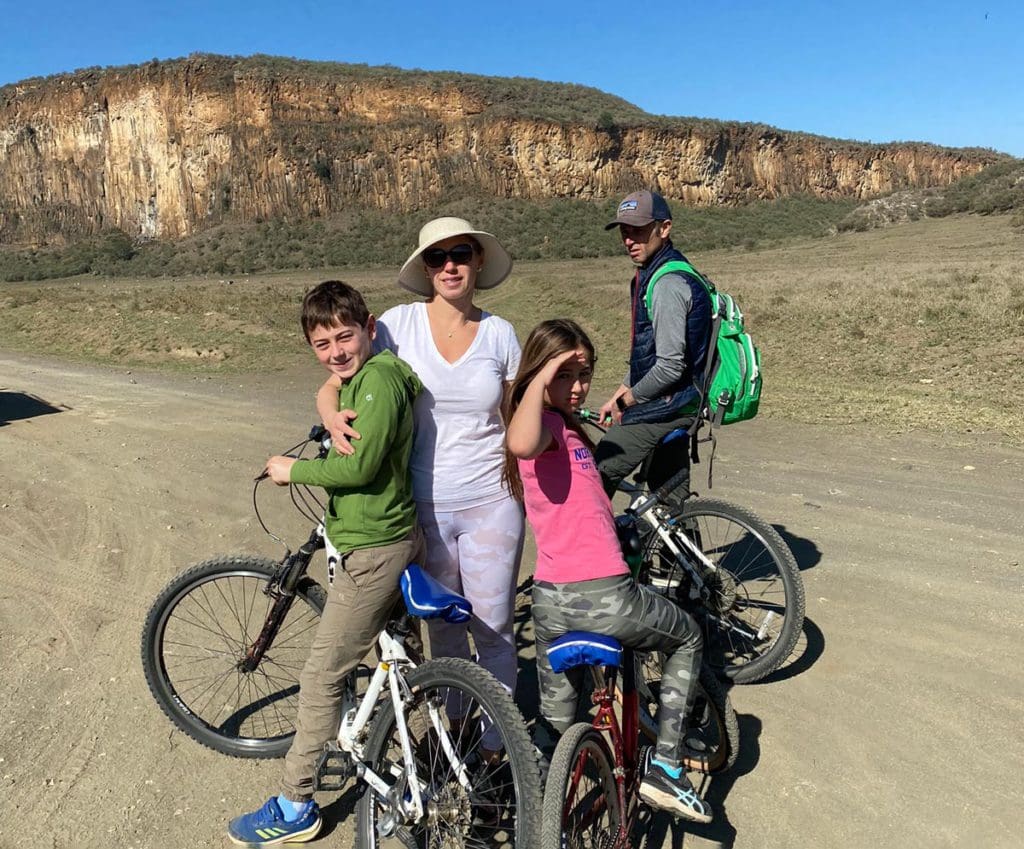 A family of four stands together with their bikes near Hells Gate National Park, one of the stops on this Kenya Itinerary for Families.