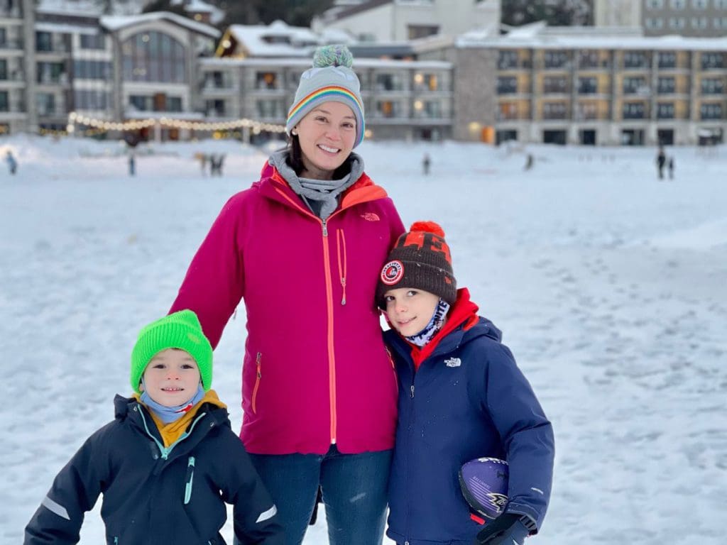 A mom stands with her two kinds on a sunny, winter day, while exploring Lake Placid.