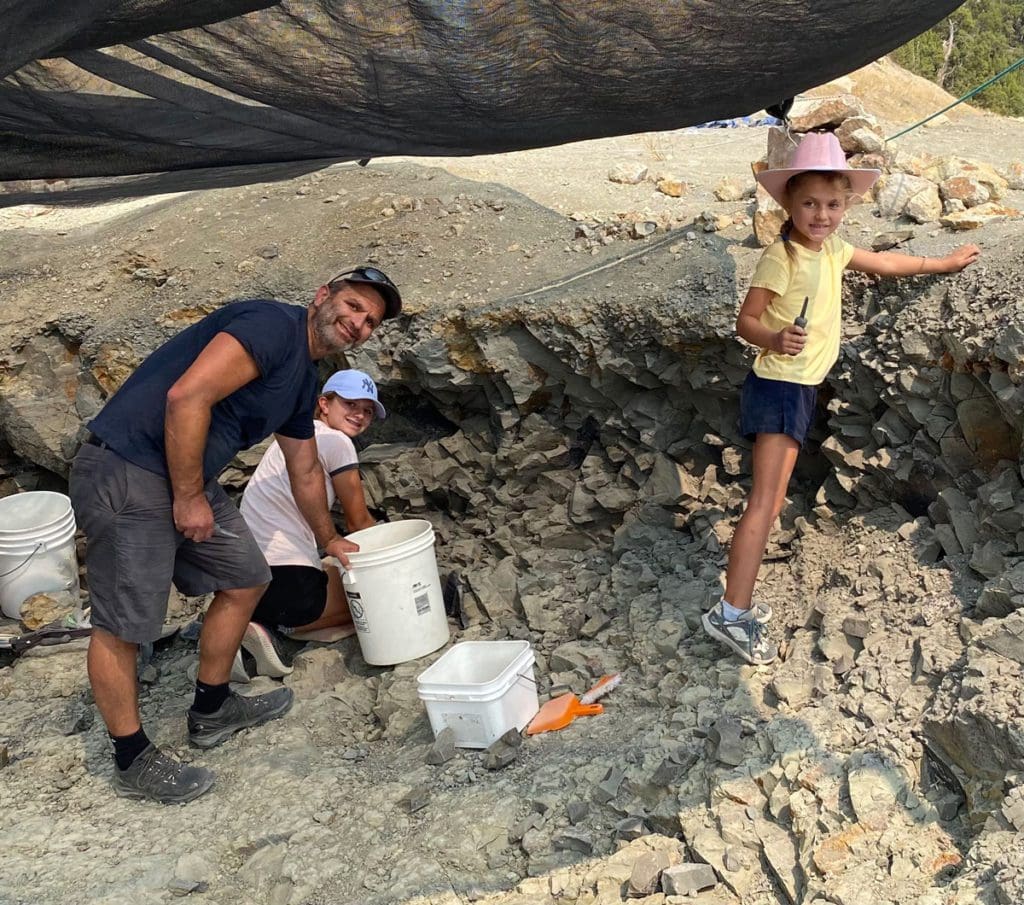 A dad and two kids dig for fossils at the Wyoming Dinosaur Center, one of the best places for a dinosaur-themed vacations in the united states for families.