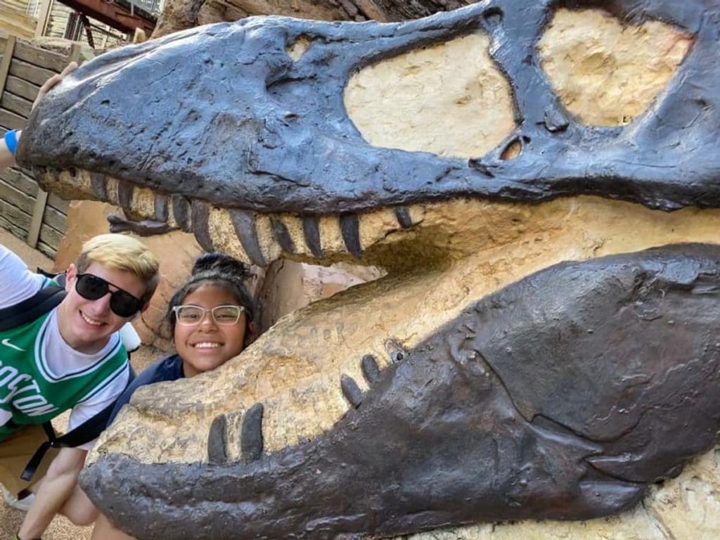 Two kids put their heads together between the teeth of a large Tex-Rex skeletal display at Animal Kingdom.