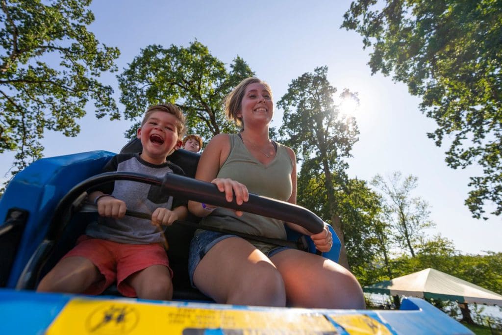 A mom and her young son ride an amusement park ride at Oaks Amusement Park.