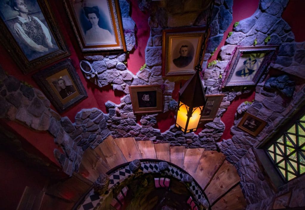 The stairwell of the Haunted Mansion-themed room at the Adventure Suites, featuring several haunting photographs on the wall, one of the best themed hotels on the East Coast for families.