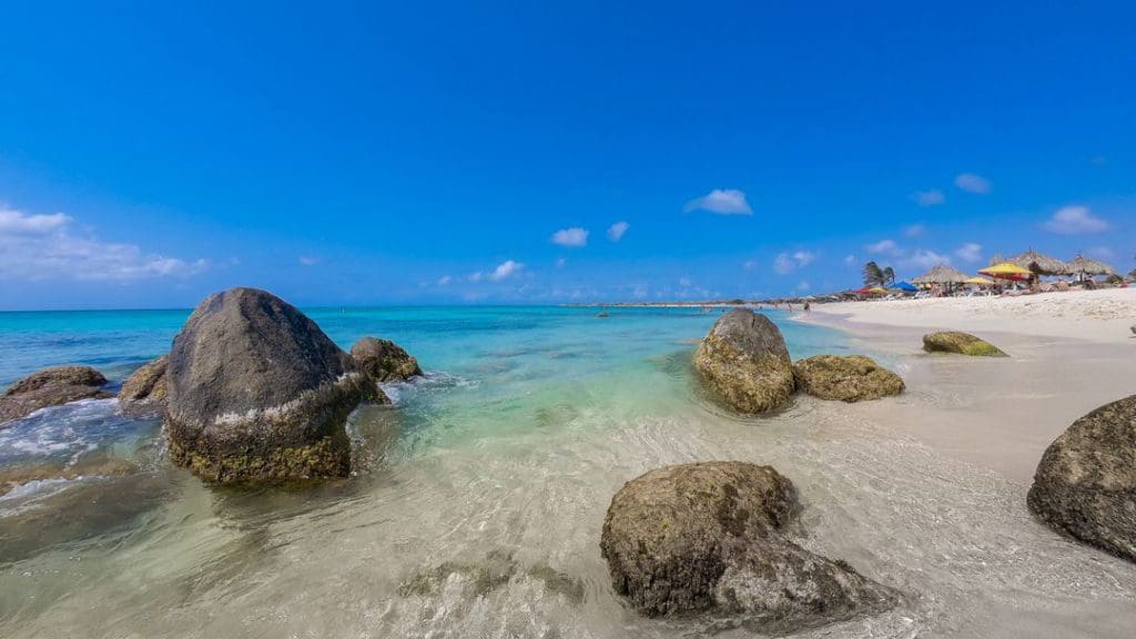Several large rocks peek out of the water at Arashi Beach, one of the best beaches in Aruba for families.