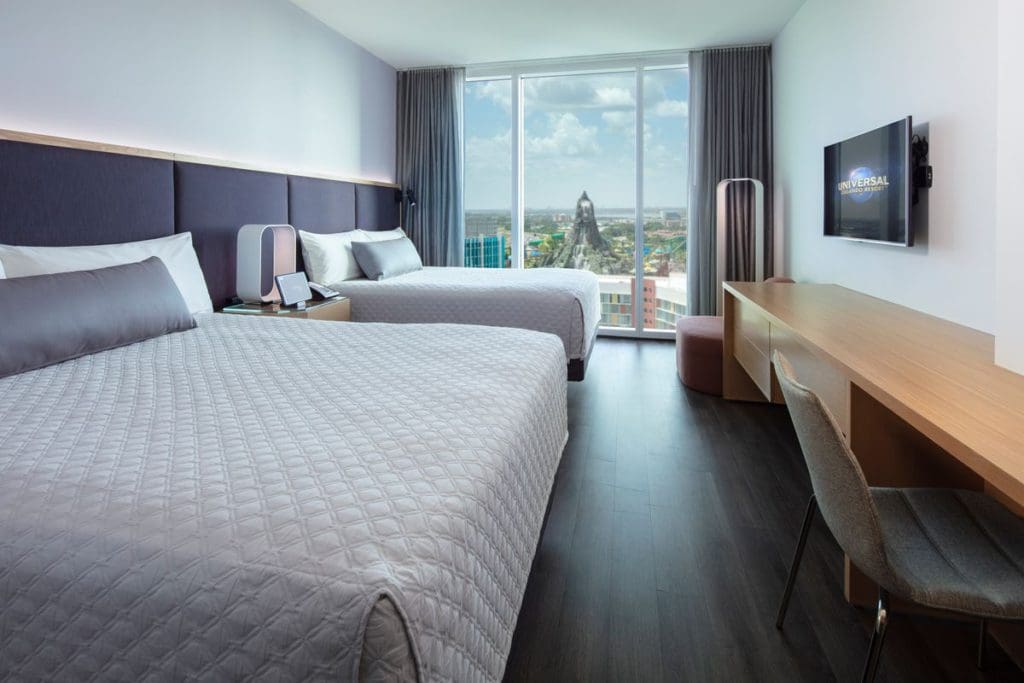Inside one of the chic, but classically designed rooms at Aventura Hotel, featuring two beds and a view of Universal Orlando through the window.