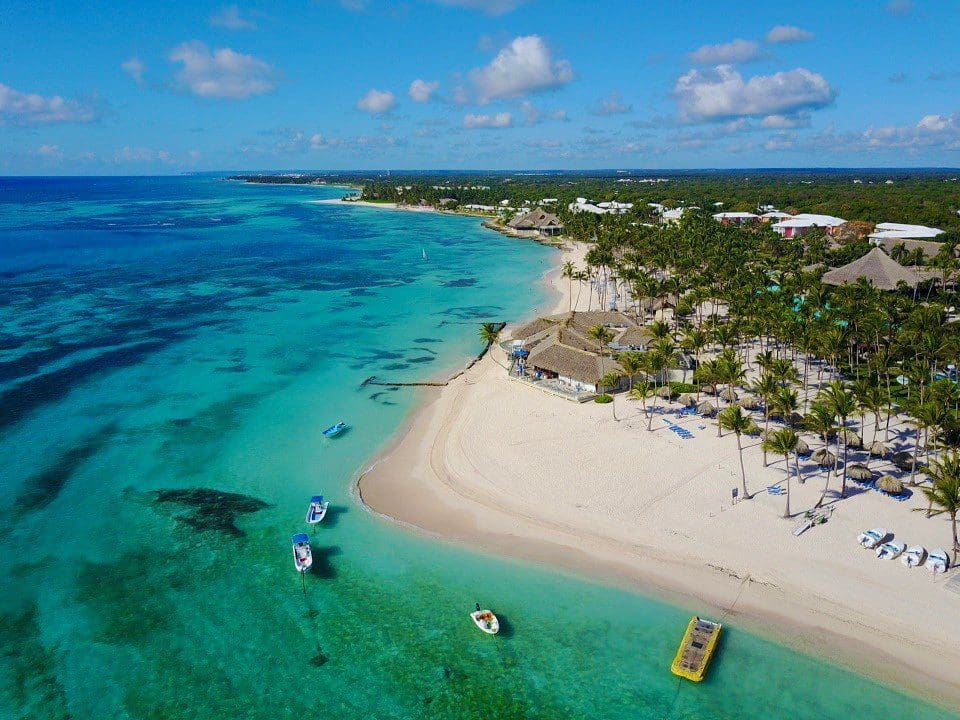An aerial view of Club Med Punta Cana, featuring a beachfront location, cabanas, and palm trees surrounding the resort buildings, one of the best all-inclusive resorts in the Caribbean for families.