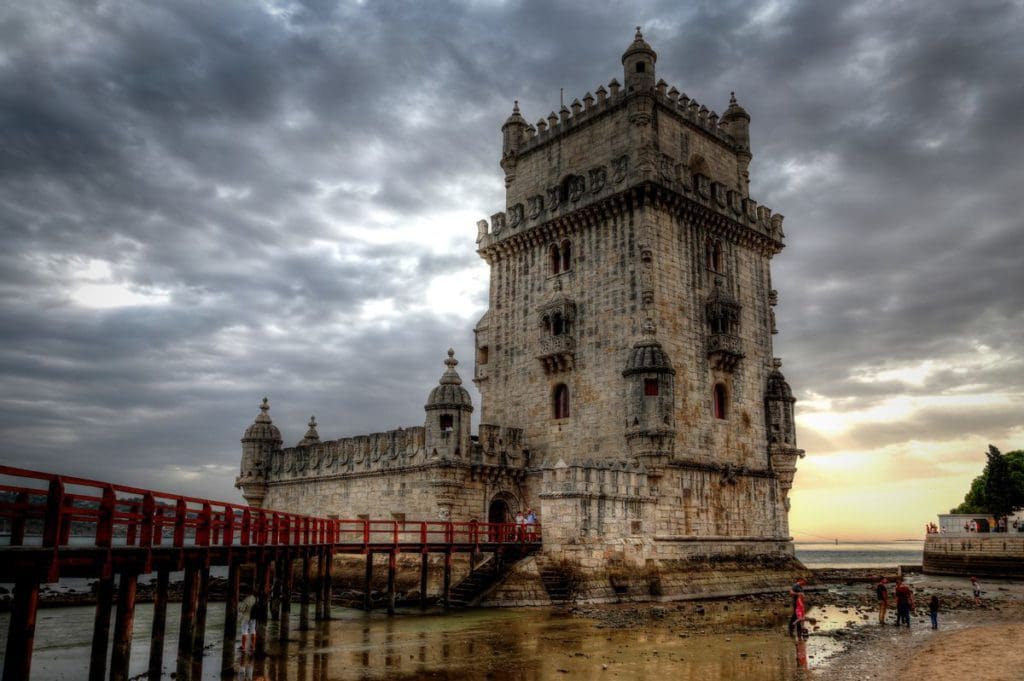 A view of a historic building in Belem, while kids walk down below along the water.