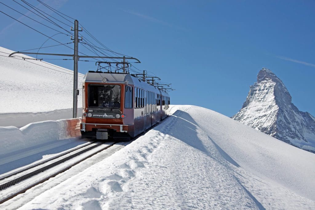 A train from the Gornergrat Bahn moves down the tracks on a sunny, winter day.