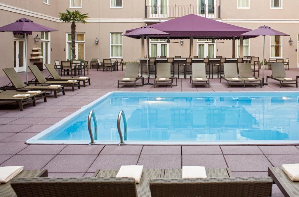 The outdoor pool at Hyatt Centric French Quarter New Orleans, featuring shaded poolside loungers.
