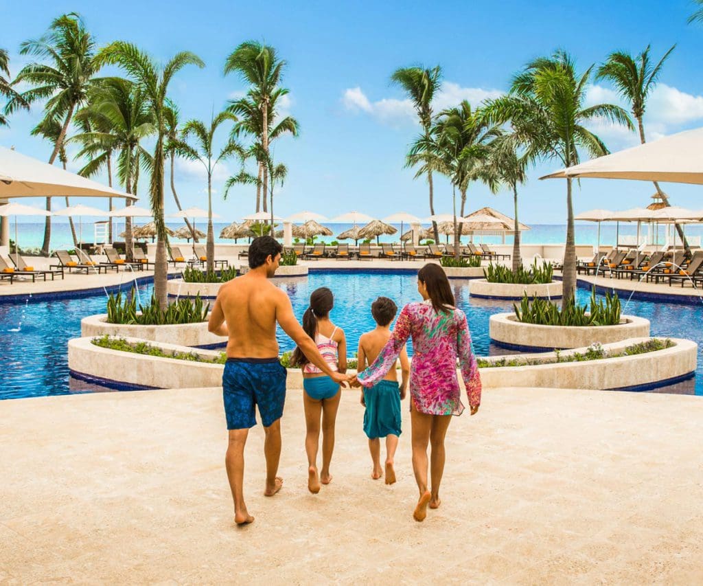 Two parents and their two children walk along the pool deck at the Hyatt Ziva Rose Hall.