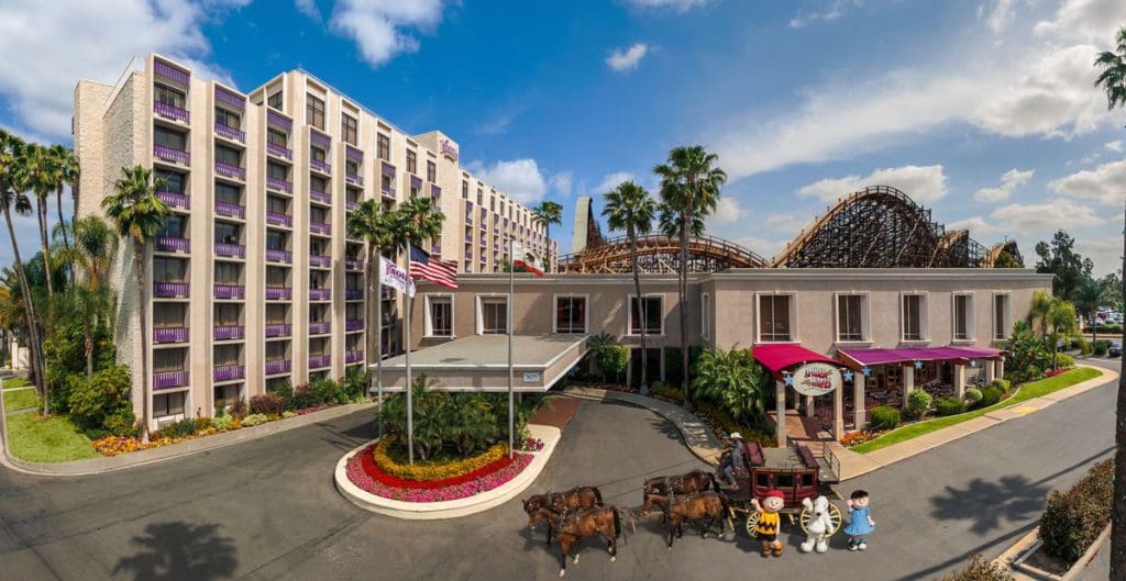 The exterior of the Knotts Berry Farm Hotel, with three Snoopy characters waving from the driveway.