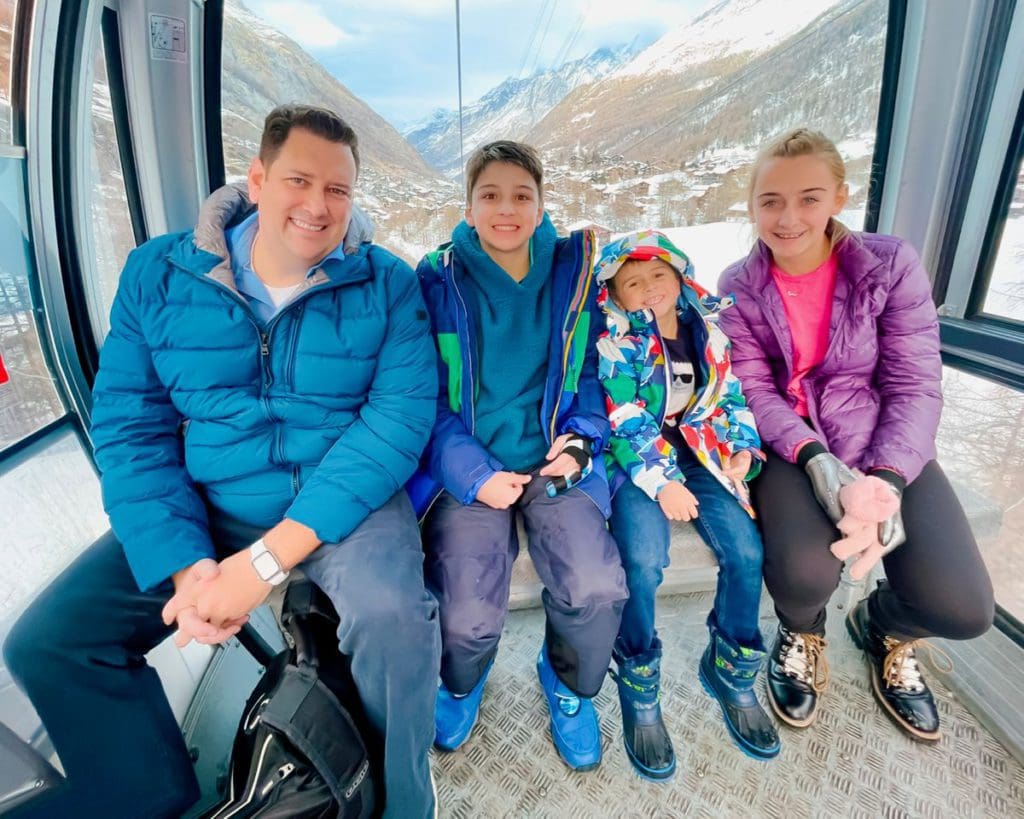 A dad and his three kids ride a gondola, while skiing in Zermatt together.