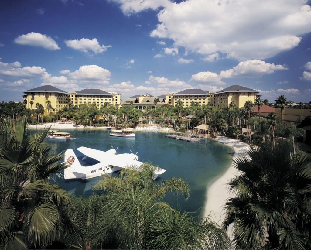 An aerial view of the Loews Royal Pacific Resort, featuring beautiful, lush grounds, and an airplane on the water.