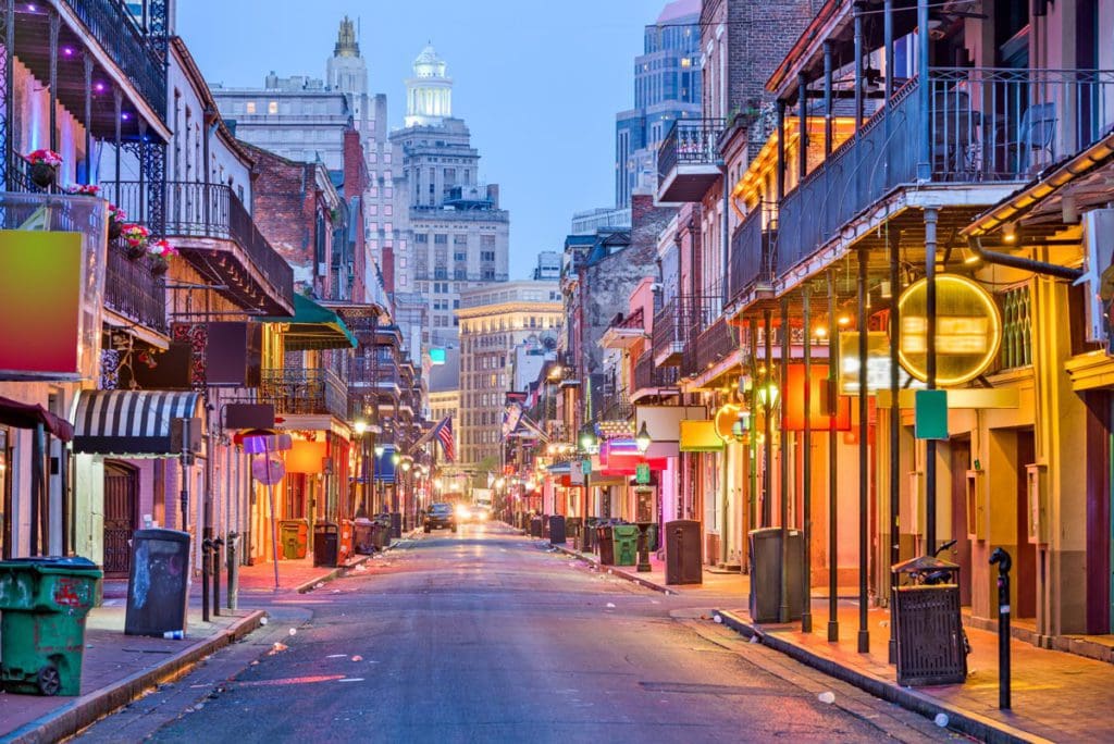A well-lit street in New Orleans at night, featuring shops and other store fronts, one of the best Moms’ Getaways or Girls’ Trip Ideas.