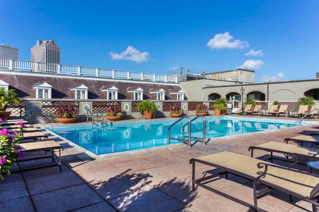 The rooftop pool at Omni Royal Orleans, featuring a large pool deck and a line of poolside loungers.