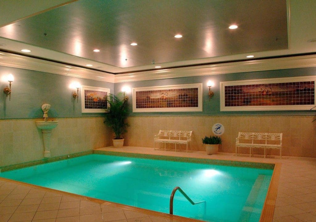 The indoor pool at The Ritz-Carlton New Orleans, featuring soft lighting and pool deck seating.