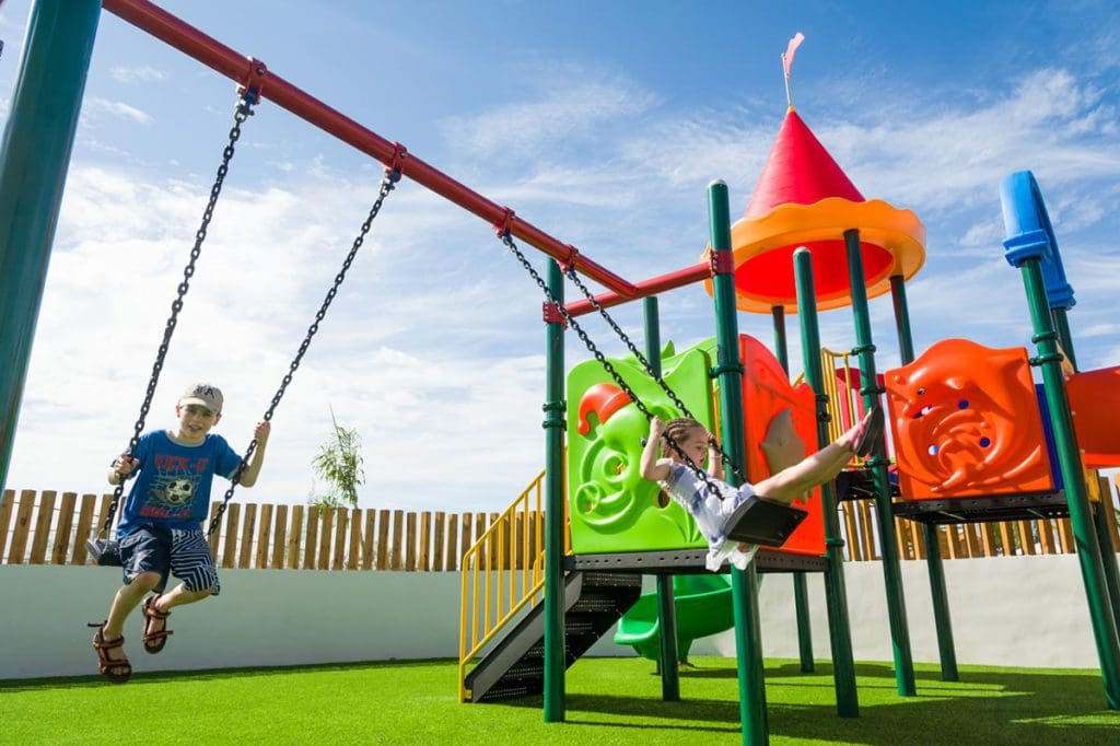 Two kids swing at the on-sight playground at the Royalton White Sands Resort.