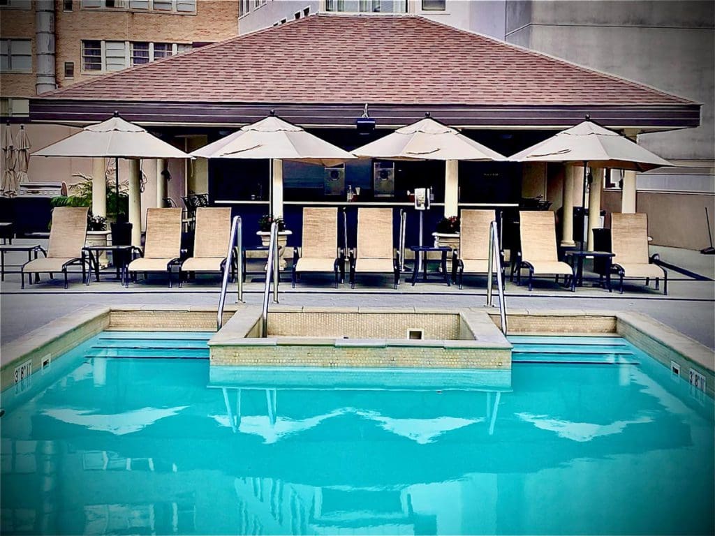 The outdoor pool at The Roosevelt New Orleans, A Waldorf Astoria Hotel, featuring a line of pool deck chairs facing the pool at one of the best hotels in New Orleans for families.