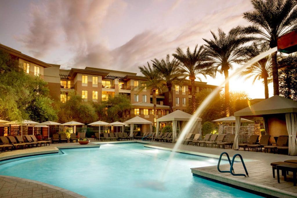 The pool and surrounding pool deck at The Westin Kierland Resort & Spa, with resort buildings behind it, at sunset.