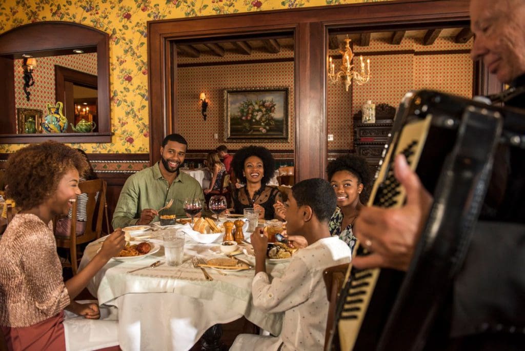 A large African-American family sits around a table eating dinner at one the best hotels for families at Universal Orlanda.