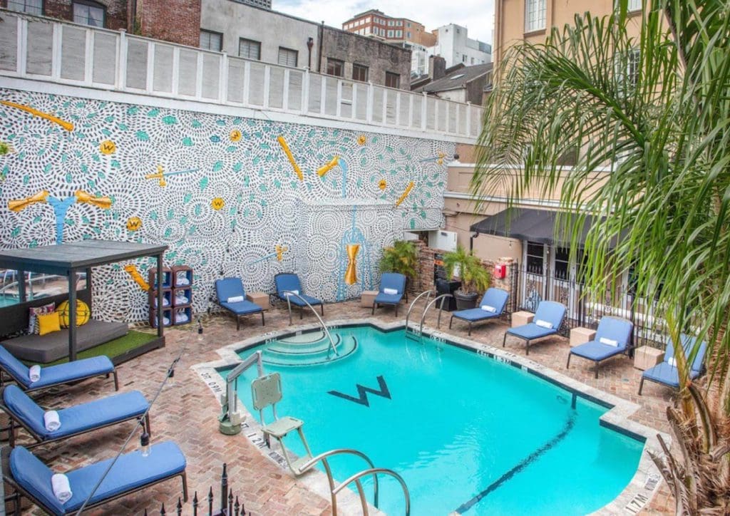 The outdoor pool, with poolside loungers and lush foliage, at The W New Orleans - French Quarter, one of the best hotels in New Orleans for families.