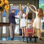 A dad leads a luggage cart inside the lobby of the Windsor Court Hotel, while his two girls follow him.