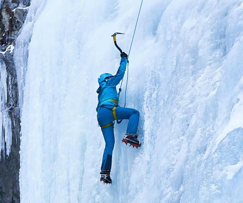 A man wearing all blue ice climbs in Switzerland.