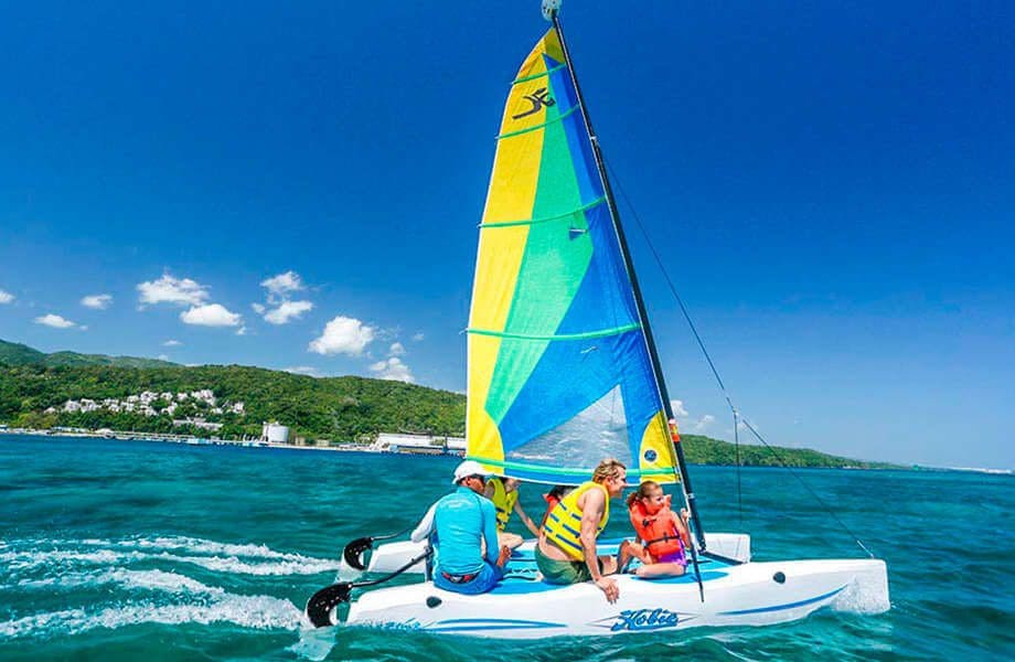 A family rides a sail boat off-shore from Moon Palace Jamaica.