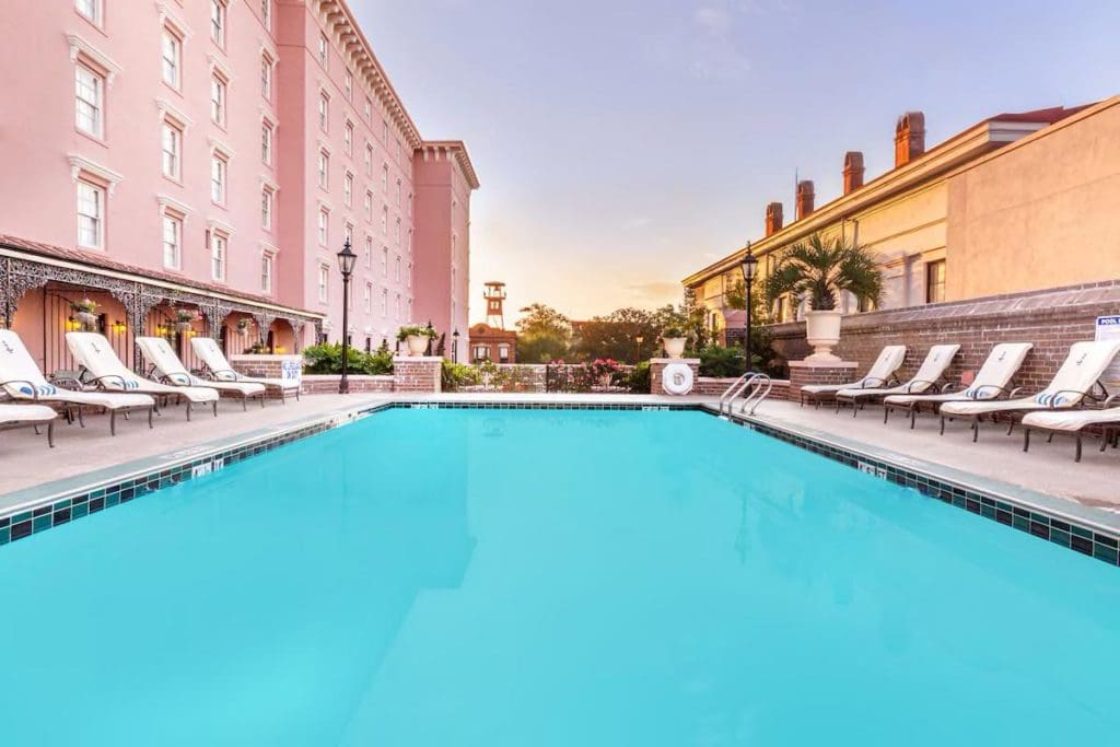 The outdoor pool at The Mills House Wyndham Grand Hotel, with pink-hued hotel buildings flanking both sides.