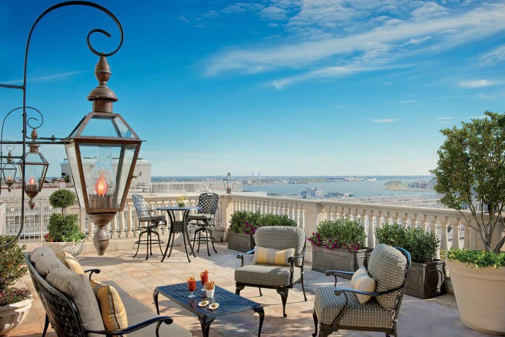 The terrace patio featuring several plush seating arrangements at The Ritz-Carlton New Orleans, with a skyline view.