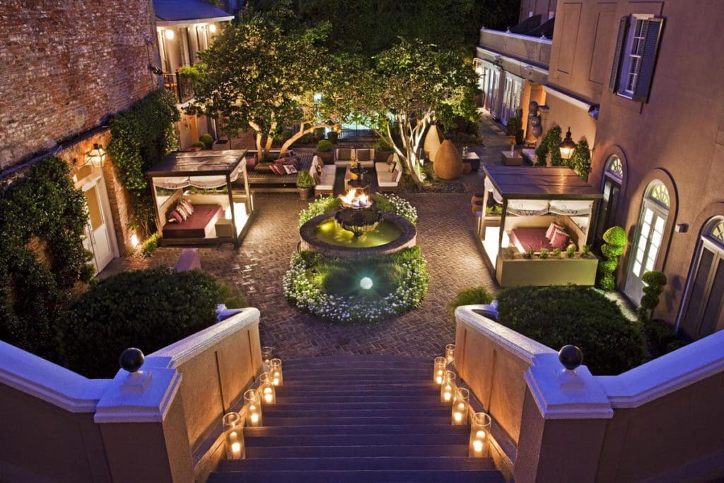 The interior courtyard at The W New Orleans - French Quarter, featuring twinkling lights, seating, and lush foliage in the center.