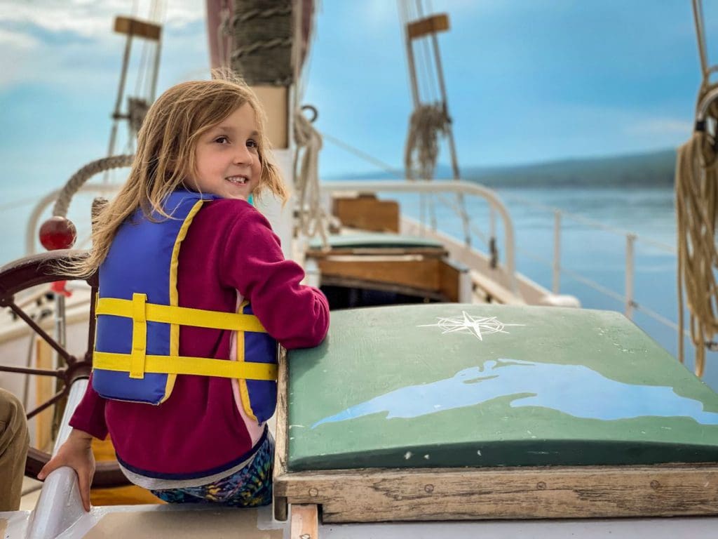 A young girl wearing a life jacket smiles as she sails along Lake Superior in a schooner, off-shore from Grand Marais, Minnesota.