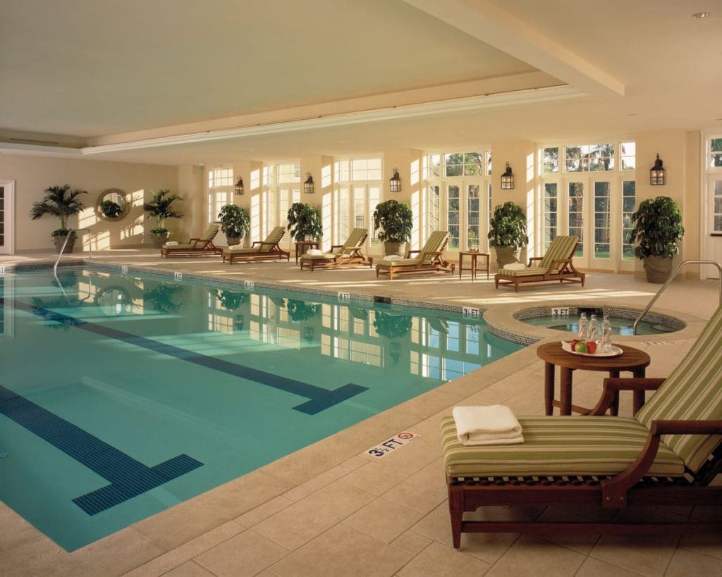 The indoor pool at Kiawah Island Golf Resort, with poolside loungers and floor to ceiling windows.